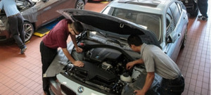 2 auto students looking at car's engine